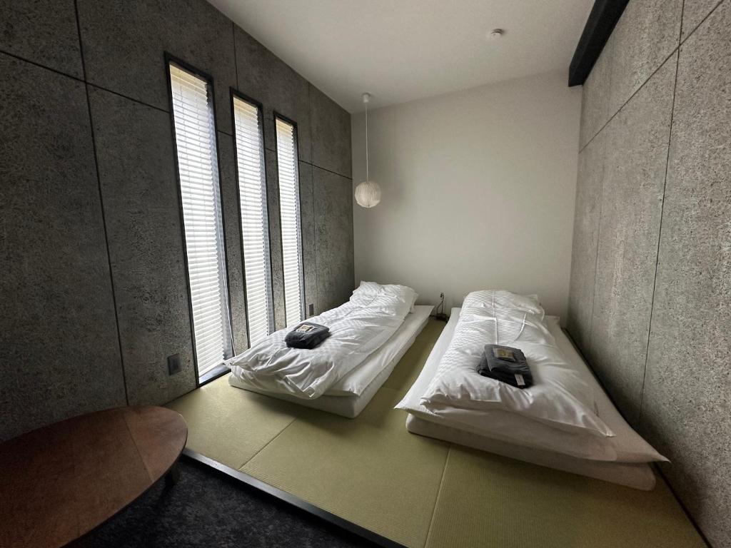 two beds in a room with two windows at The EKAI in Toyohashi