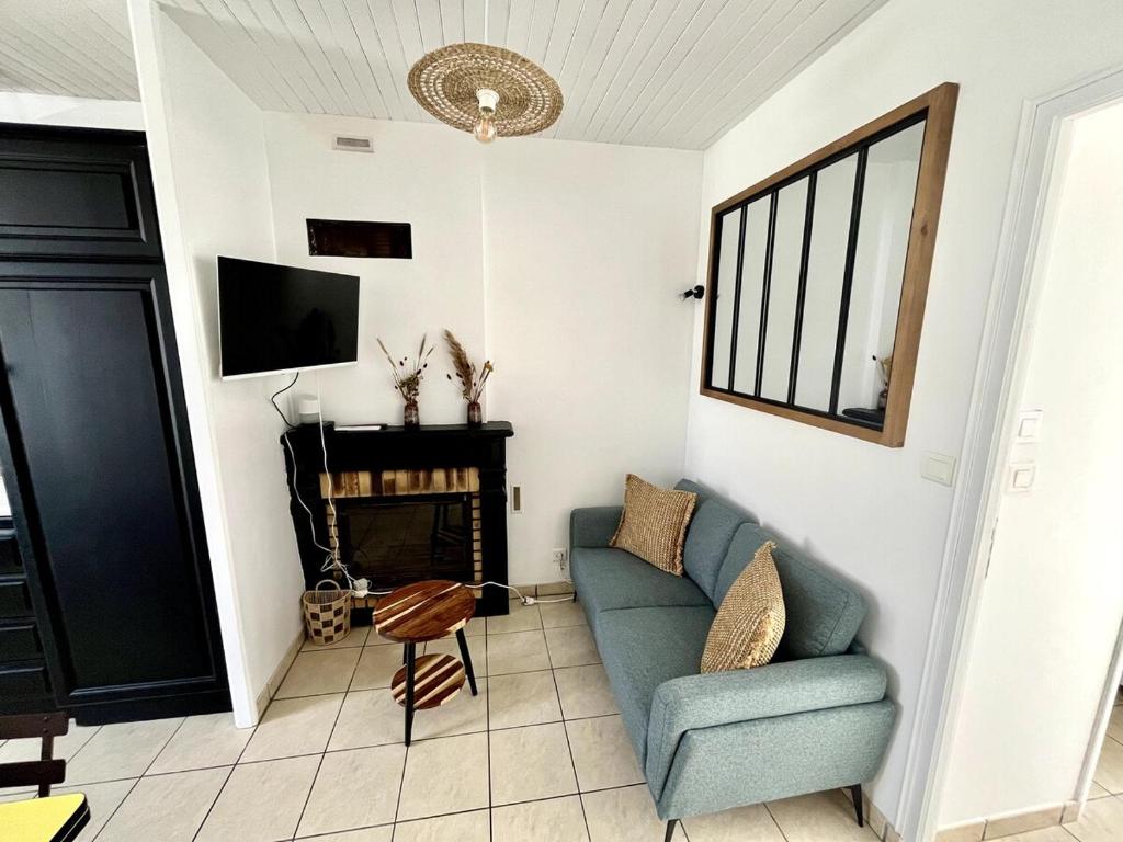 Una sala de estar con un sofá azul y un televisor en L'Instant Terrière - Quartier Calme - Proche plage, en La Tranche-sur-Mer