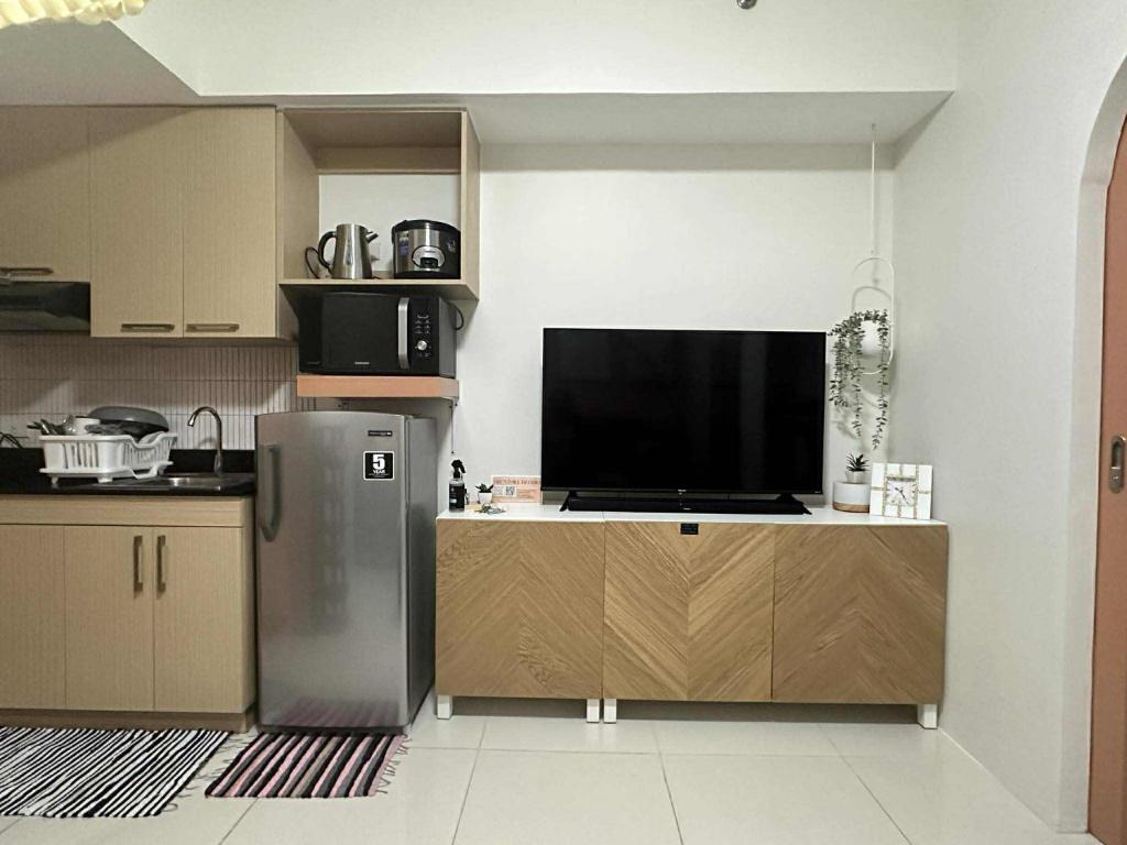 eine Küche mit Kühlschrank und Flachbildfernseher in der Unterkunft Suite Escapes at Brenthill Baguio with Balcony in Baguio City