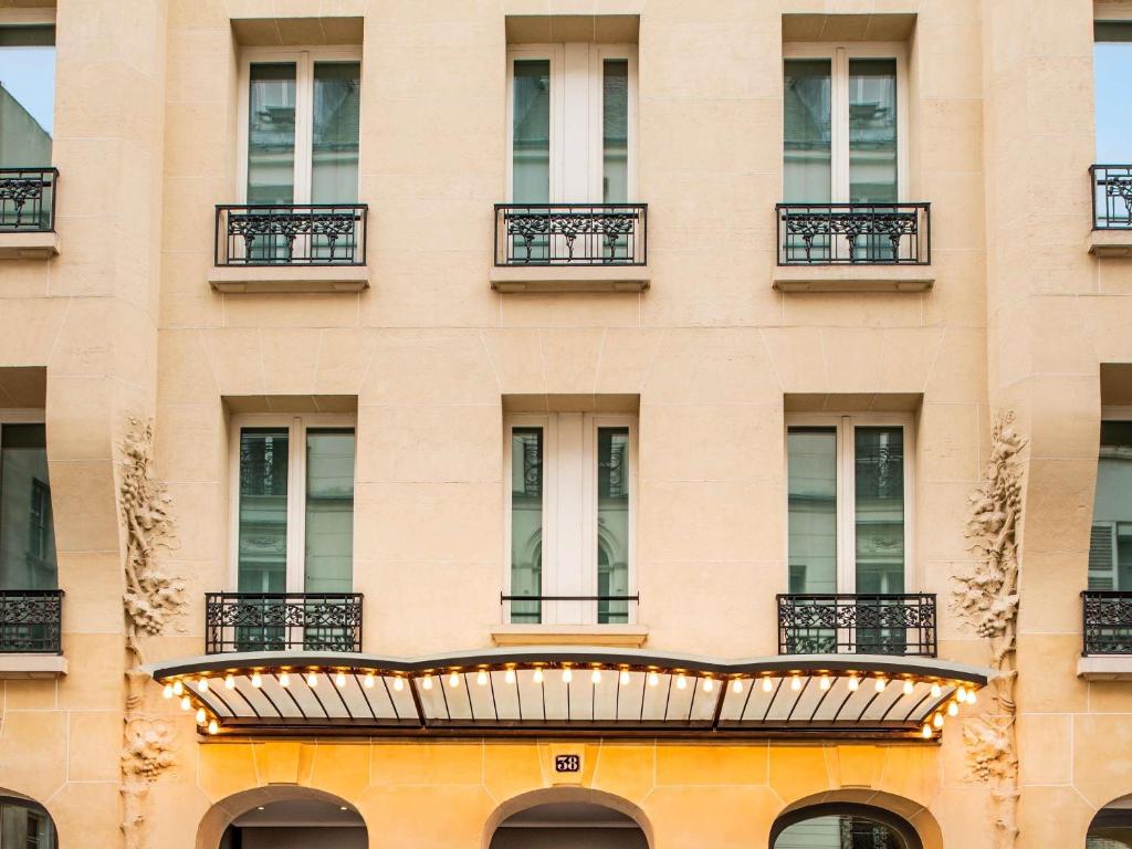 a facade of a building with windows and a balcony at l'Echiquier Opéra Hotel Paris - MGallery Collection in Paris