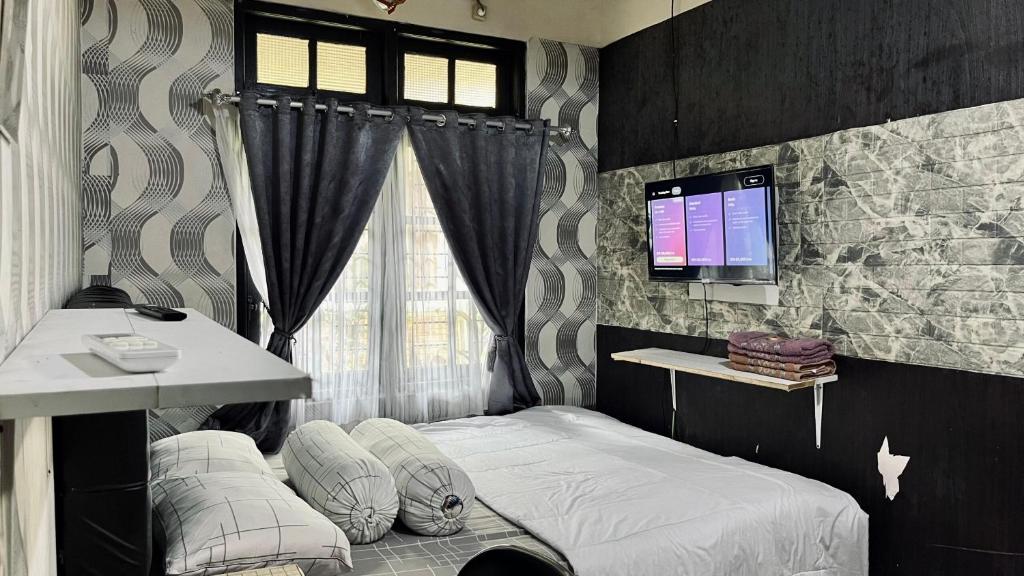 a bedroom with a bed and a desk and a tv at Ngampilan Homestay Jogja in Ngabean