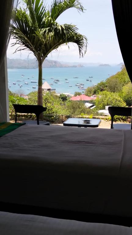 a table with two benches and a view of the ocean at La Colina Komodo Hotel in Labuan Bajo