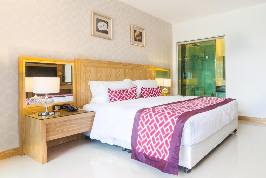 a bedroom with a large bed with red and white pillows at The Par Phuket Hotel in Ban Thung Thong
