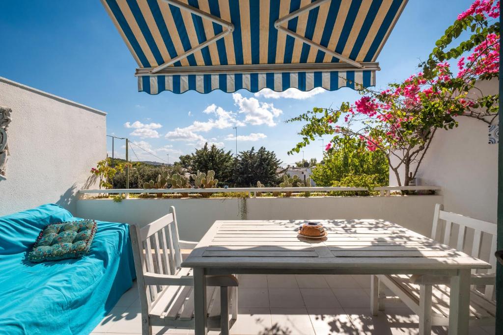 einen Tisch und Stühle auf einem Balkon mit Sonnenschirm in der Unterkunft Sea View Terrace in Santa Caterina di Nardò