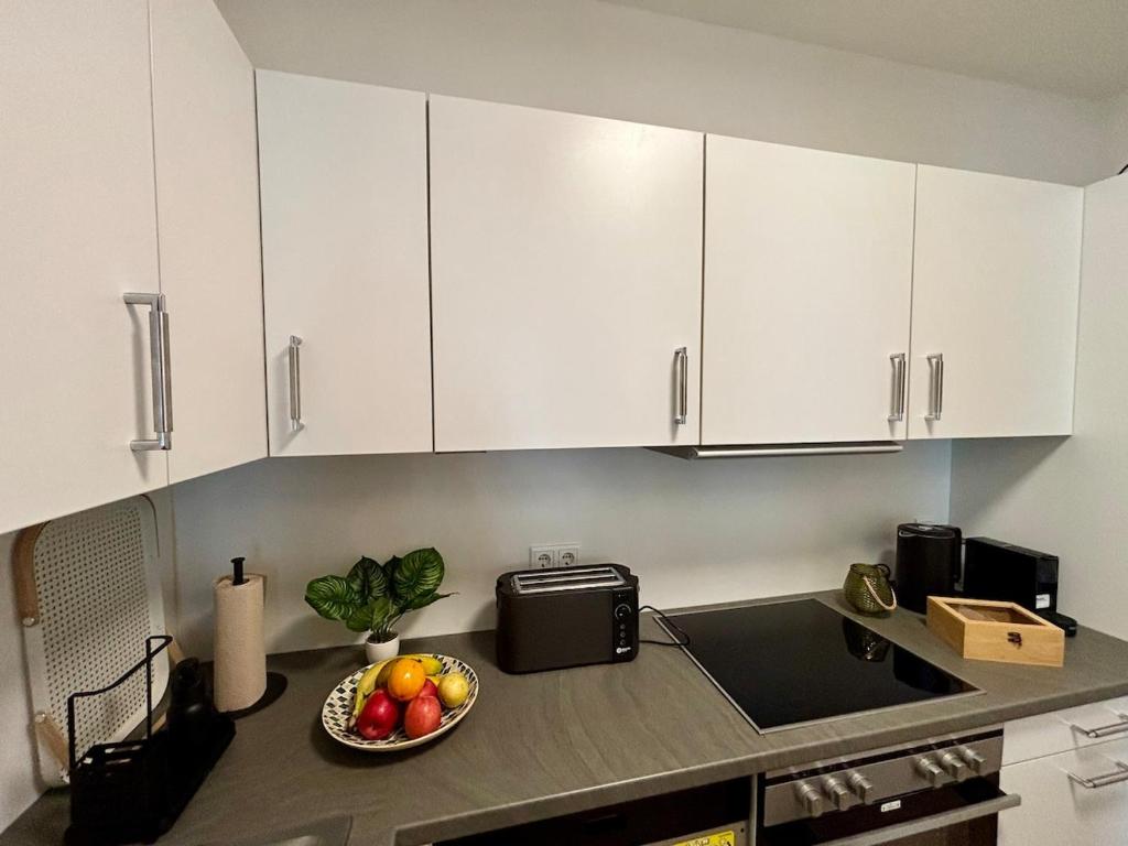 a kitchen with white cabinets and a bowl of fruit at Zentral und Stilvoll Nahe Kurpark und Bali Therme in Bad Oeynhausen