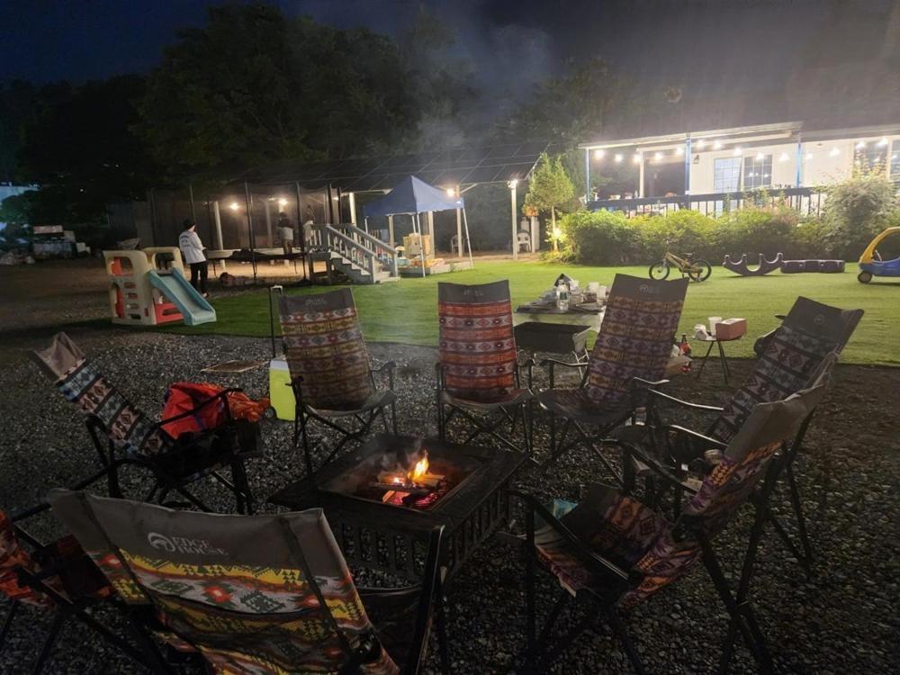 a group of chairs and a fire pit in a yard at night at Taean Lily Pension in Taean