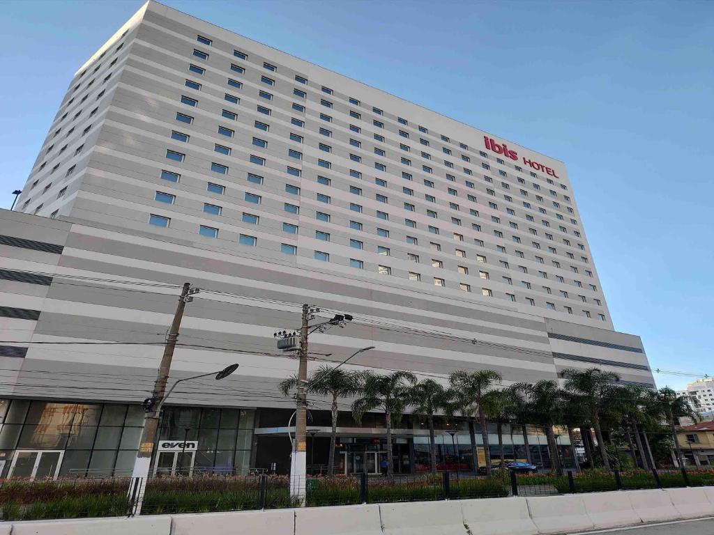 a large hotel building with palm trees in front of it at ibis Sao Paulo Ibirapuera in Sao Paulo