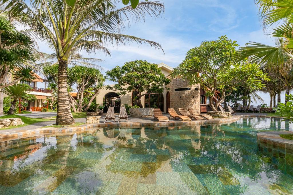 a swimming pool in front of a house with palm trees at Sun Village Beach Resort in Tuy Hoa