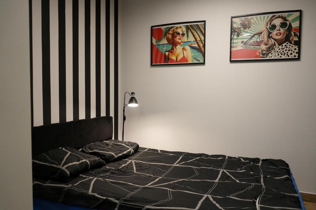 a bedroom with three pictures on the wall and a bed at Wyjątkowy apartament z prysznicem pośrodku na wyjątkowe wieczory in Łódź