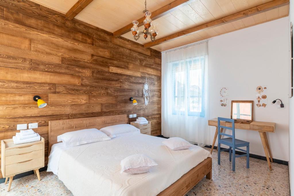 a bedroom with a wooden wall with a bed and a desk at Sa Omu 'Eccia in Villagrande Strisaili