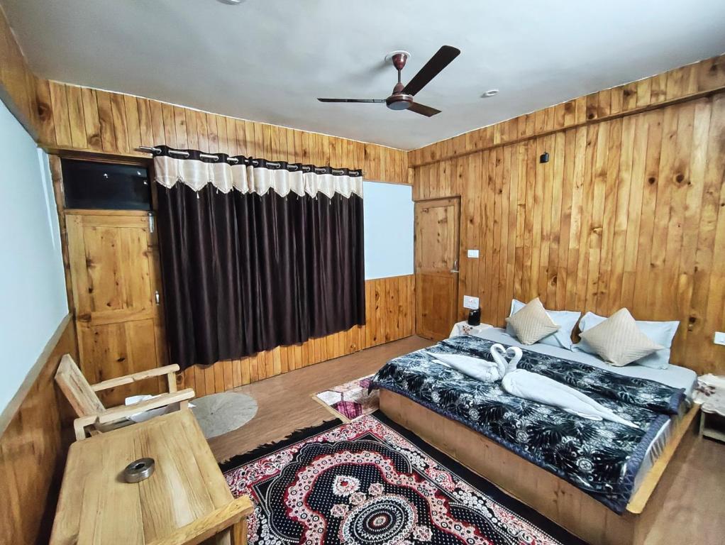 Un dormitorio con una cama y un ventilador de techo. en The clifftonn stays, en Jibhi