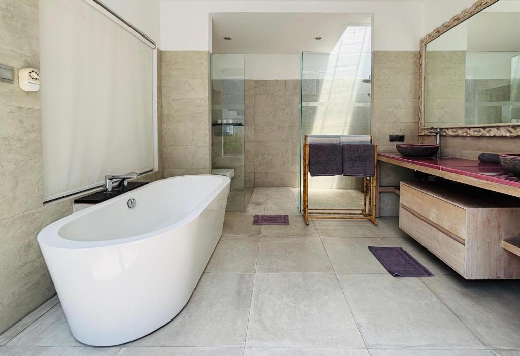ein Badezimmer mit einer großen weißen Badewanne und einem Waschbecken in der Unterkunft Zoe Villa Canggu Bali in Canggu