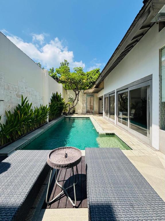 a swimming pool with a table next to a house at Zoe Villa Canggu Bali in Canggu