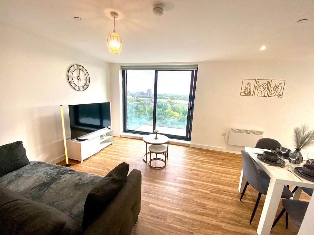 een woonkamer met een bank, een tafel en een klok bij Lux Stylish 2 Bed High Rise with Parking and Balcony in Manchester