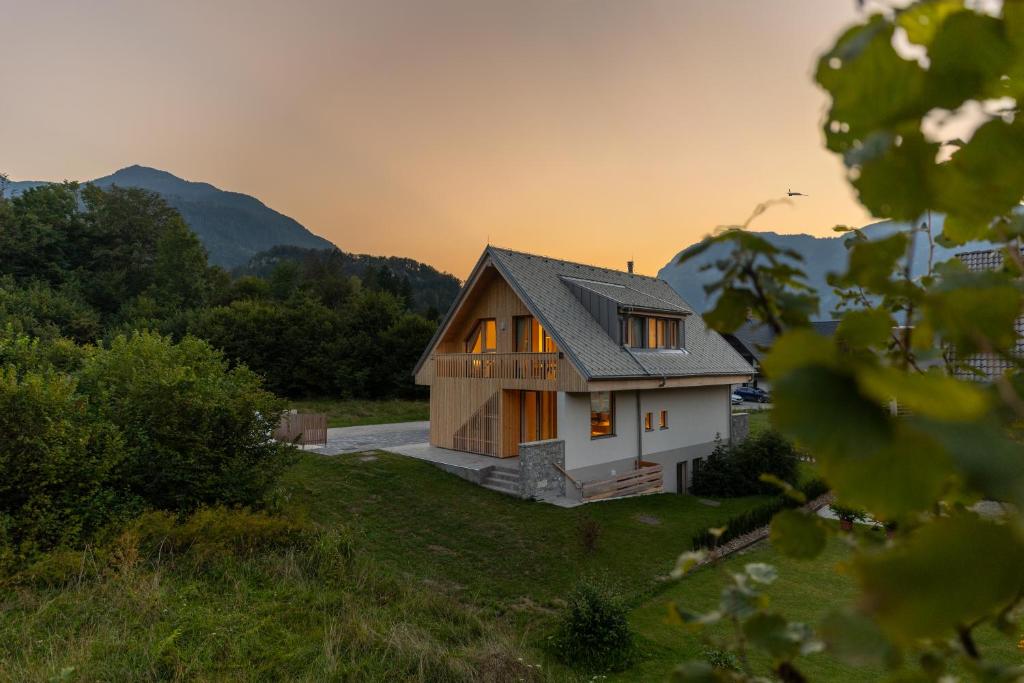 a house on a hill with the sunset in the background at Chalet Bohinj Bliss Wellness and view of Triglav in Bohinj