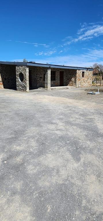 a stone building with a roof on a parking lot at Die Steenkamps in Sutherland