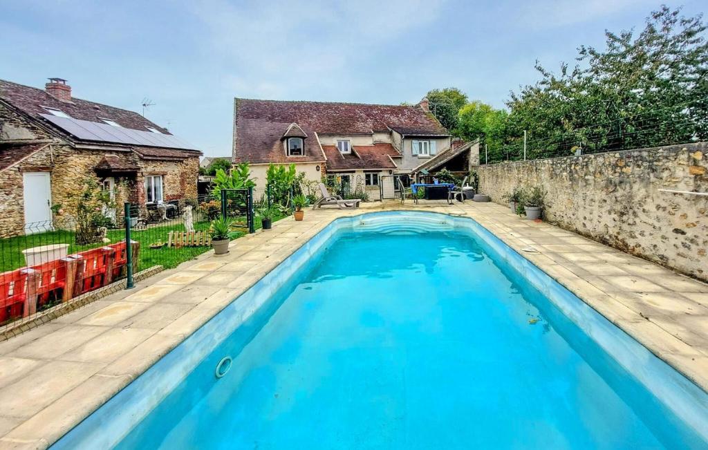 a large blue swimming pool in a yard with houses at Nice Home In Boissy Le Châtel With Swimming Pool in Boissy-le-Châtel