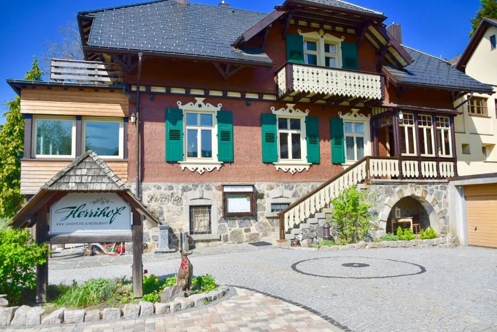 a large wooden house with green shuttered windows at Hotel & Chalets Herrihof in Todtnauberg