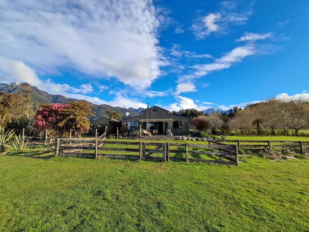 a house in a field with a fence at Waimanu Guest House in Franz Josef