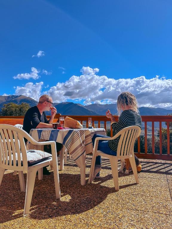 two people sitting at a table on a deck at Le cocon du Canigou in Font-Romeu