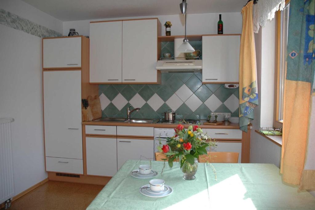 a kitchen with a table with a vase of flowers on it at Limerhof in Waischenfeld