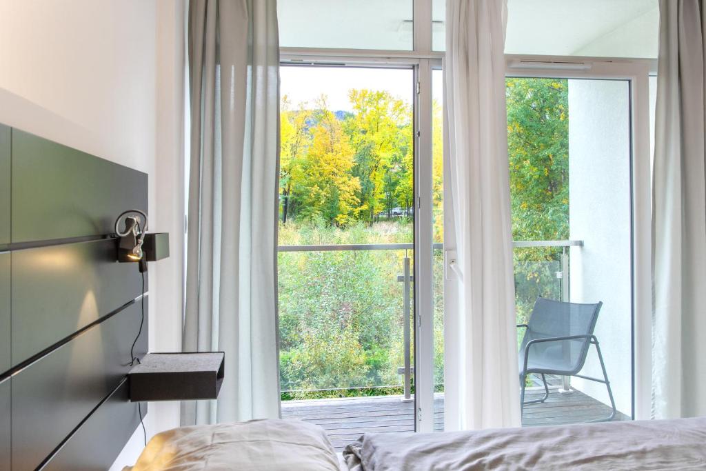 ein Schlafzimmer mit einem Bett und einem großen Fenster in der Unterkunft Szyndzielnia Park no 23 # z kortem tenisowym, rowerownią # LUX # nestapartmenty in Bielsko-Biała