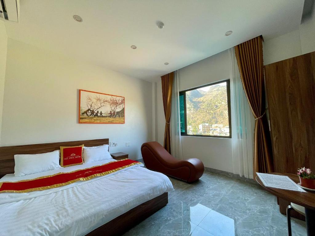 a bedroom with a bed and a chair and a window at Khách sạn Đức Phúc in Dồng Văn