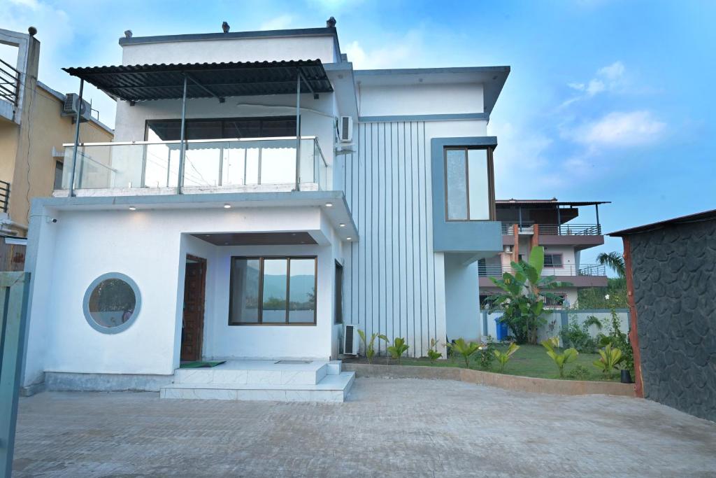 ein weißes Haus mit einem Balkon darauf in der Unterkunft Miraval Vista in Malavli