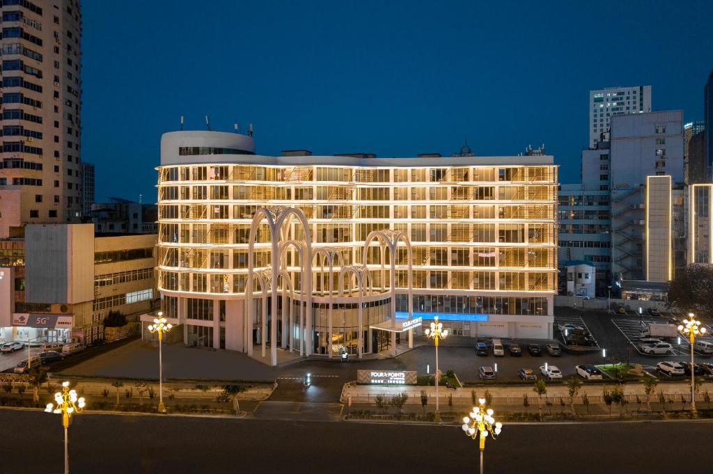 Un edificio iluminado en una ciudad por la noche. en Four Points by Sheraton Yantai Zhifu, en Yantai