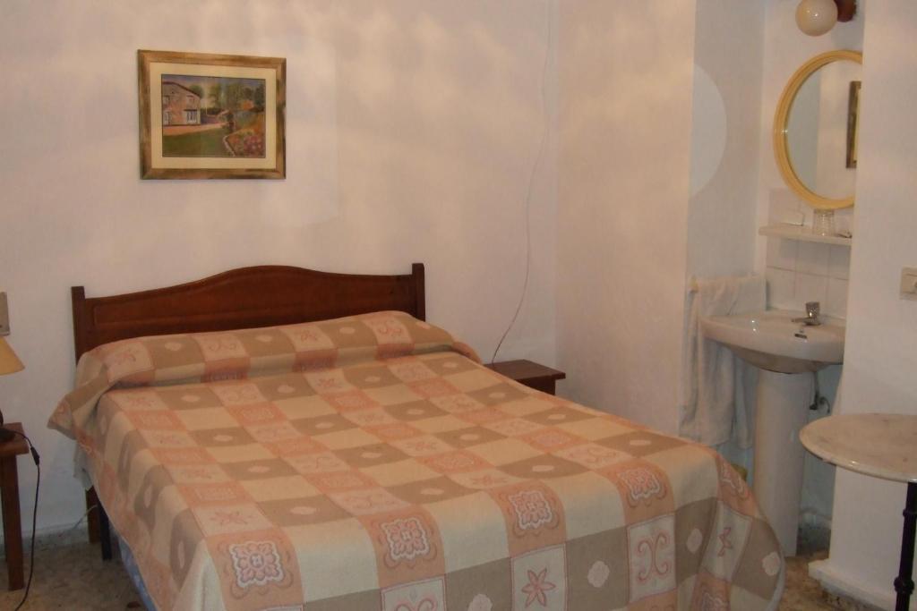 a bed in a room with a white bedspread at Hostal Alcázar in Córdoba