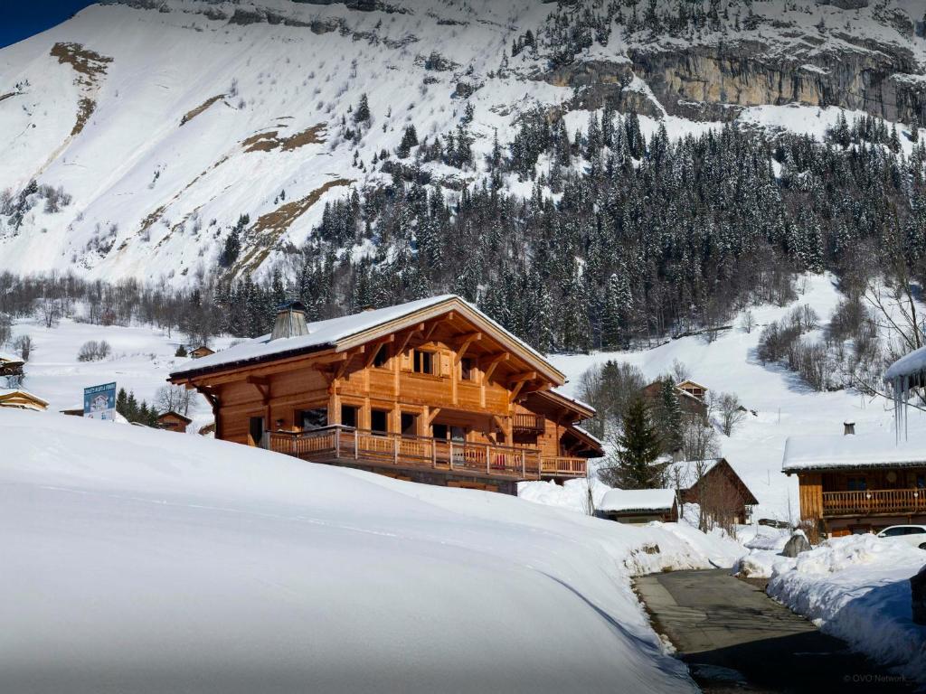 Una cabaña de troncos en la nieve con una montaña en Chalet Le Charmieux - OVO Network, en Le Grand-Bornand