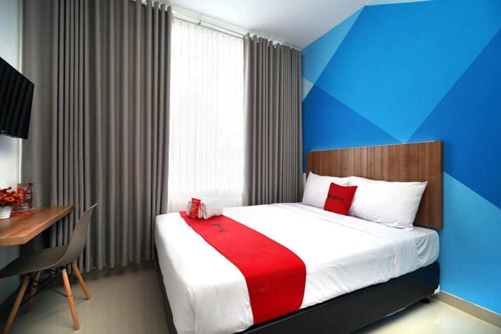 a bedroom with a bed with a red and white blanket at RedDoorz Plus @ Terban Residence in Yogyakarta
