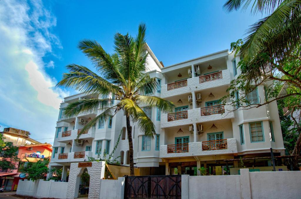 a building with a palm tree in front of it at Hotel Pajaros Blu in Calangute