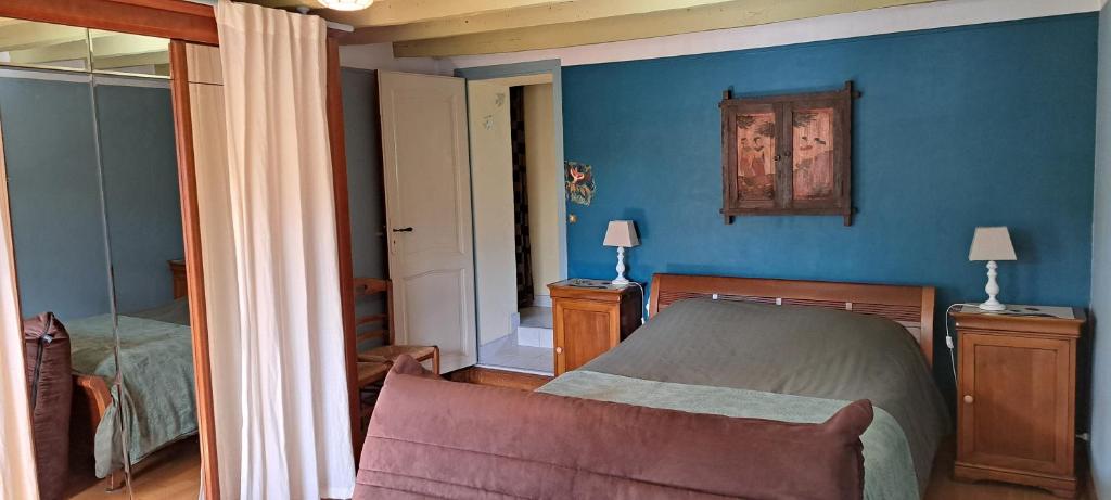 een slaapkamer met blauwe muren en een bed en een spiegel bij La Vallée du Cher in Monthou-sur-Cher