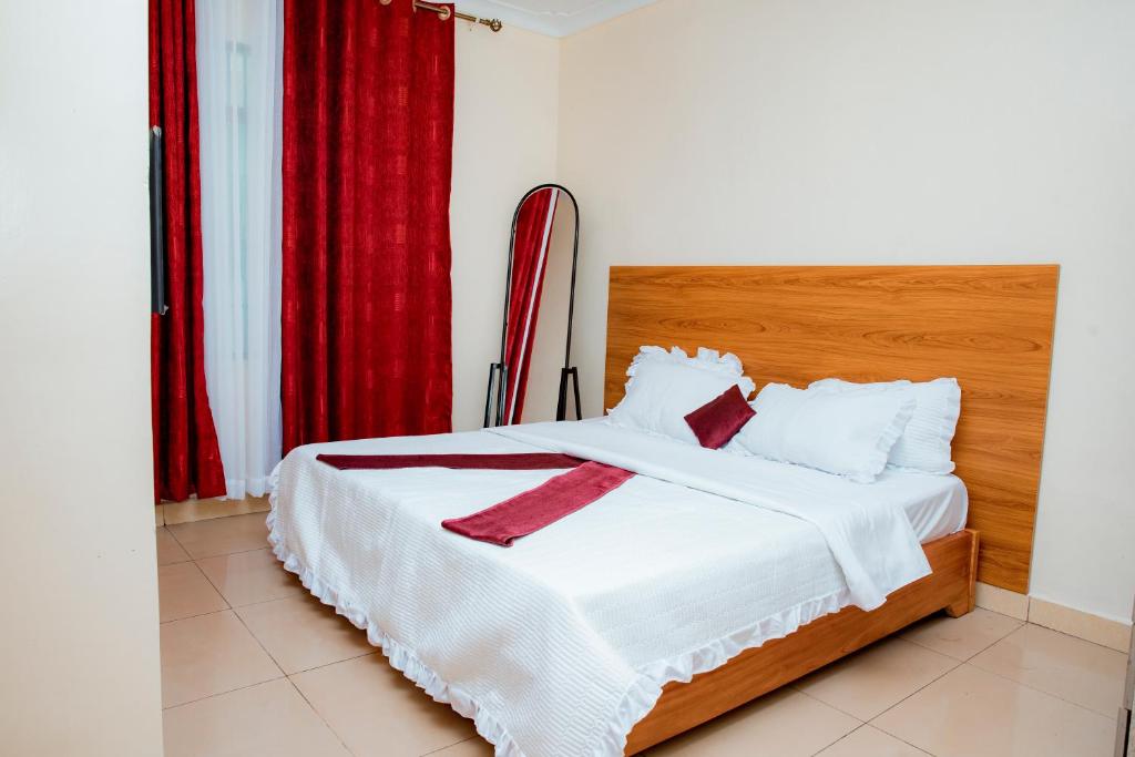 a bedroom with a white bed with a red curtain at THELIGHT HOTEL KIGALI Rwanda in Kigali