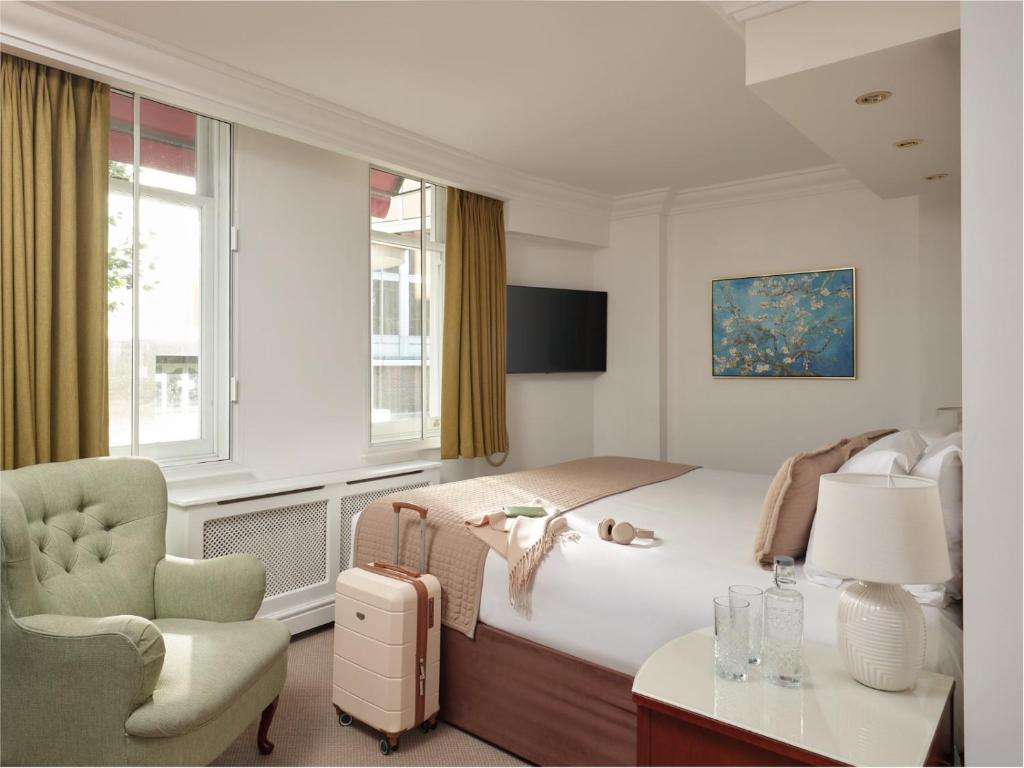 ein Schlafzimmer mit einem Bett, einem Stuhl und einem Tisch in der Unterkunft The Prime London Hotel in London