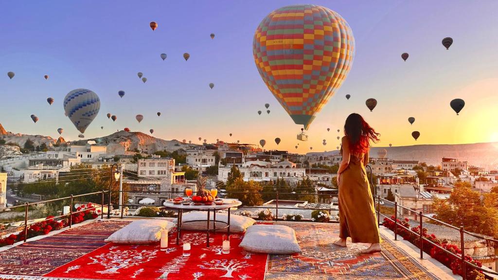 a woman standing on a balcony looking at hot air balloons at Design Cave Hotel in Goreme