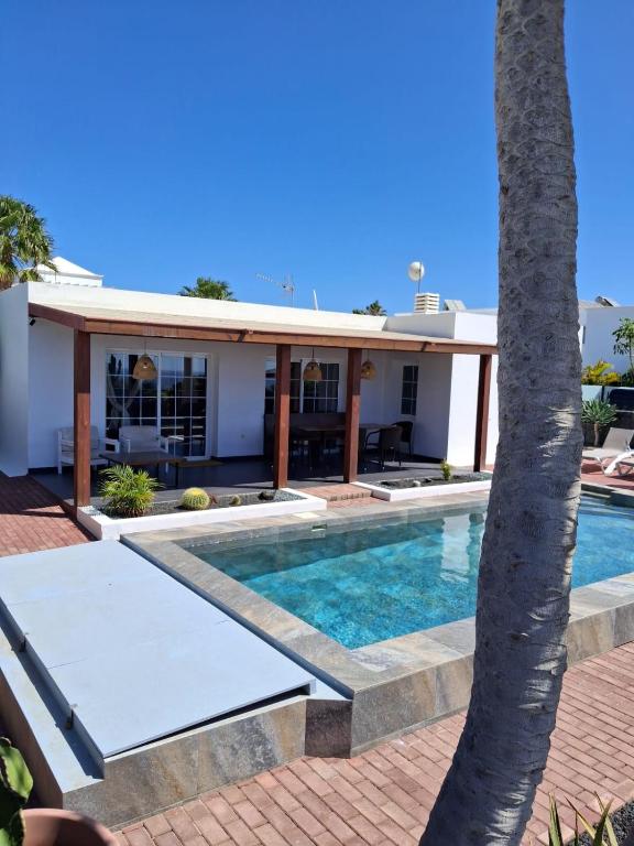 a house with a swimming pool and a palm tree at Villa Pol Lanzarote in Puerto Calero
