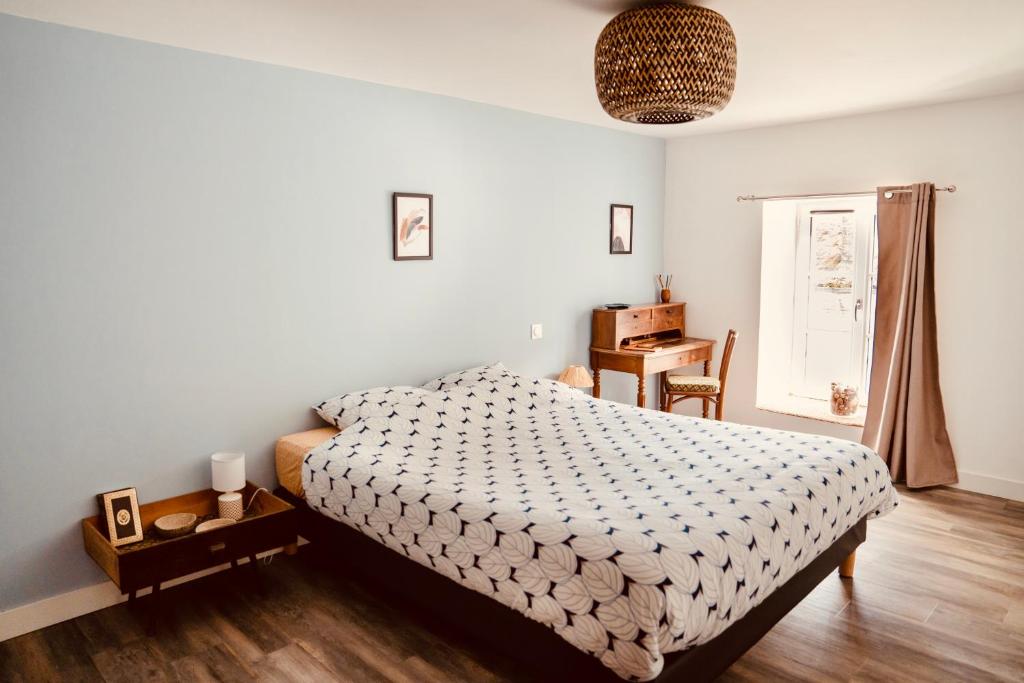 a bedroom with a bed and a table and a window at Grande maison de ville MALO LEONE 250m2 pour 15 personnes proche du Puy du Fou in Mauléon