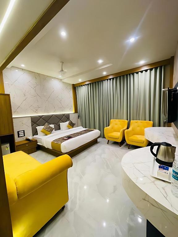 a hotel room with a bed and two yellow chairs at Glitz T2 Grand-Next to Intl Airport in Mumbai
