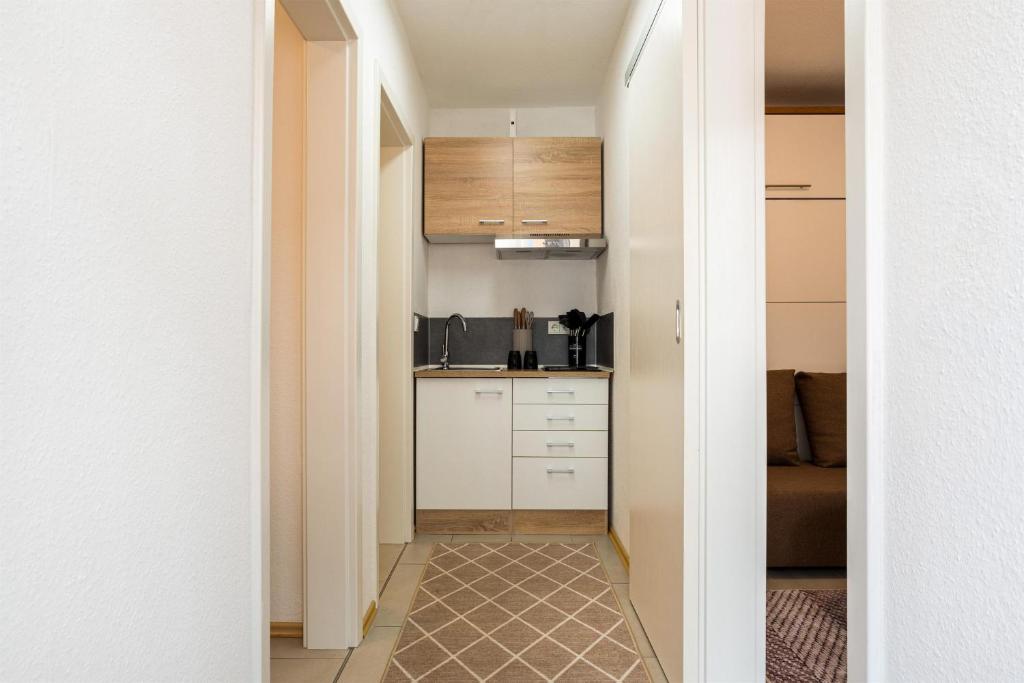 een hal die leidt naar een keuken met witte kasten bij Ferienwohnungen Meerzeit in Burhave