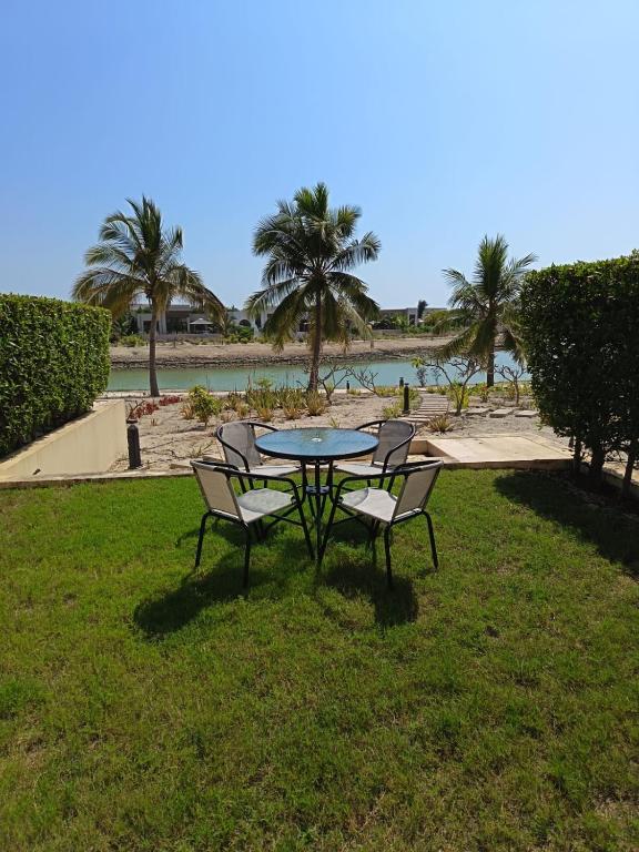a table and chairs in the grass next to a beach at Mokango Apartment Hawana Salalah in Salalah