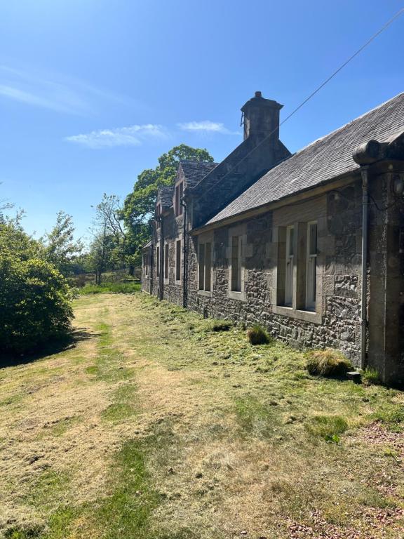 une rangée de maisons en pierre sur un chemin de terre dans l'établissement Laundry Cottage, à Lanark
