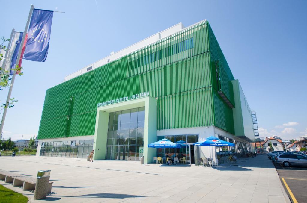 a green building with blue umbrellas in front of it at Sport Hotel Ljubljana in Ljubljana