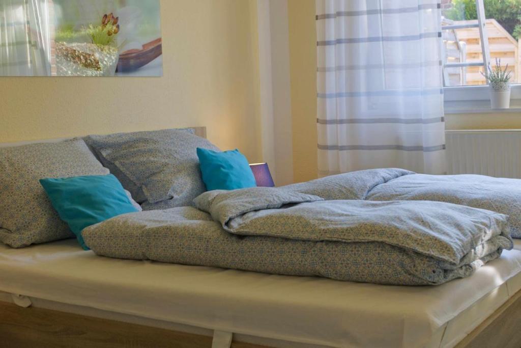 a bed with blue pillows on top of it at Inselblume 38 - Zentrale Ferienwohnung in Burg mit Garten in Burg auf Fehmarn