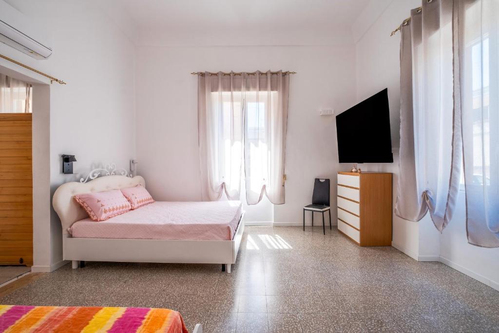 Un dormitorio blanco con una cama y un televisor. en Suite Biancolino, en Nardò