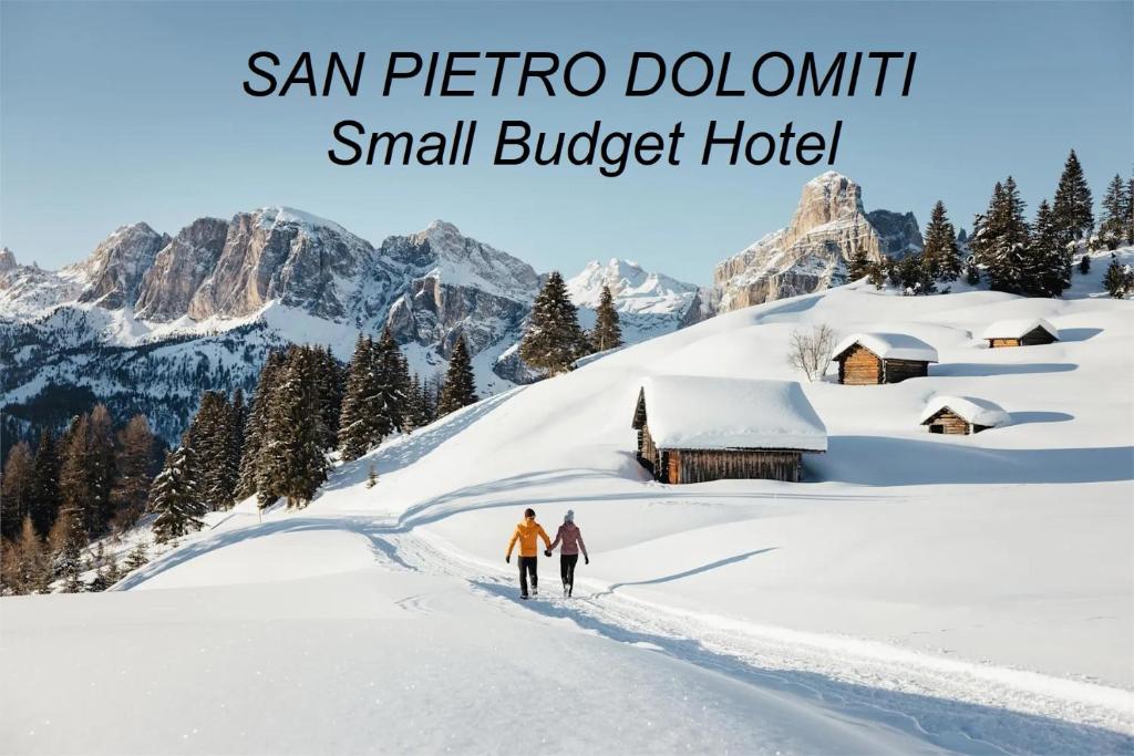 two people walking in the snow in front of a small budget hotel at SAN PIETRO DOLOMITI Small Budget Hotel in Ortisei