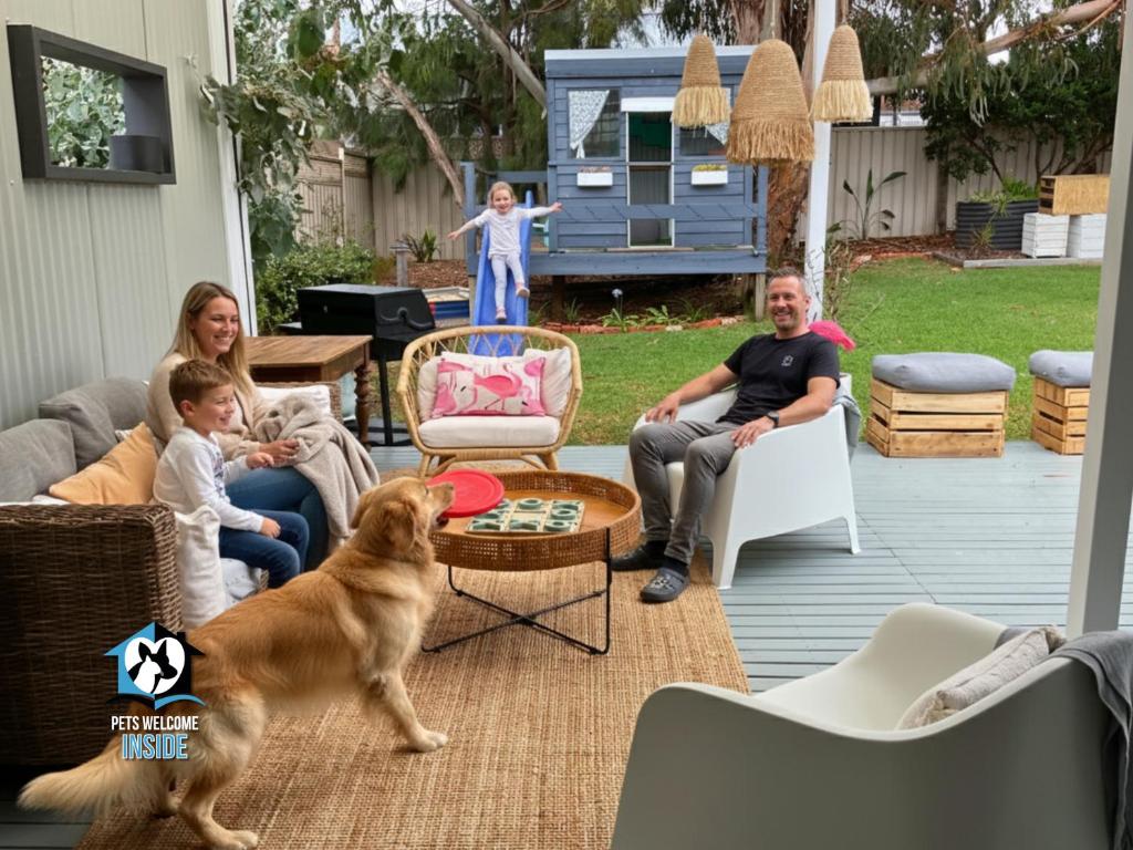 una familia sentada en un patio con un perro en Saltwater Sunsets Seaside Haven with Ocean Views, en Victor Harbor