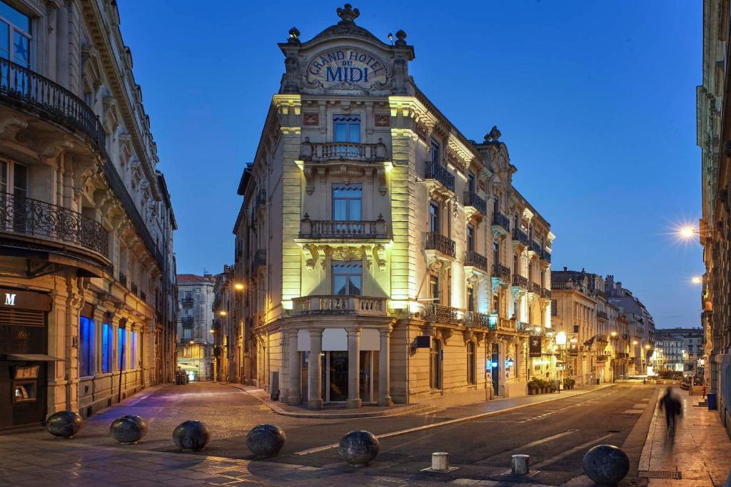 a tall building with a clock tower on a street at Grand Hôtel du Midi Montpellier - Opéra Comédie in Montpellier