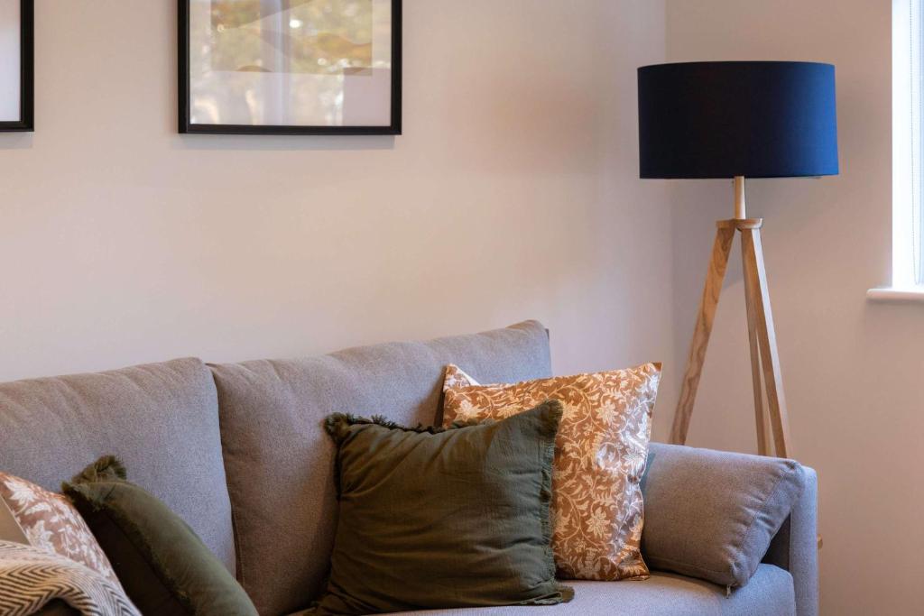 a blue couch with pillows and a floor lamp at Fabulous 2BR Apartment at Trinity Point Gravesend in Gravesend